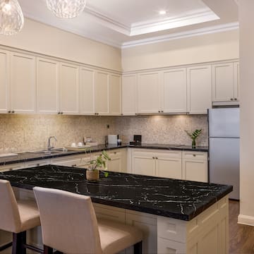 a kitchen with a black countertop and chairs