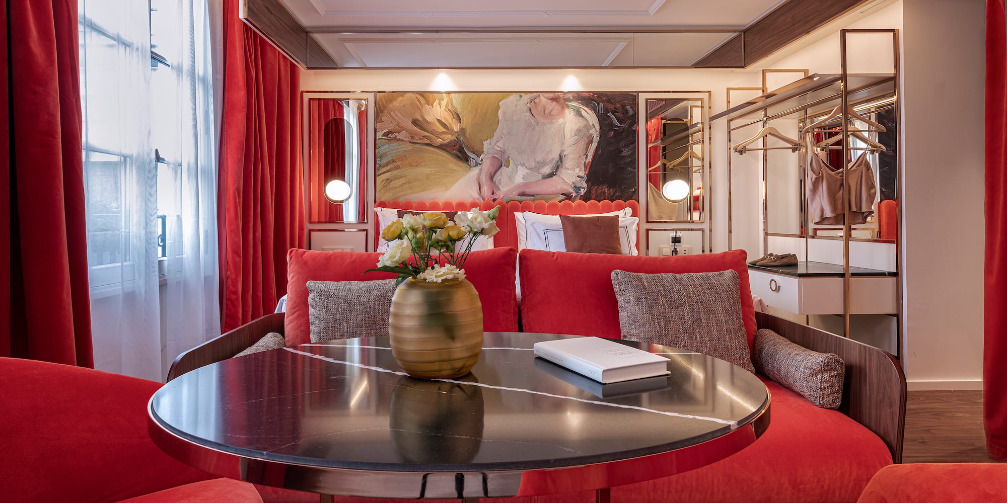 a room with red couches and a table with a vase of flowers