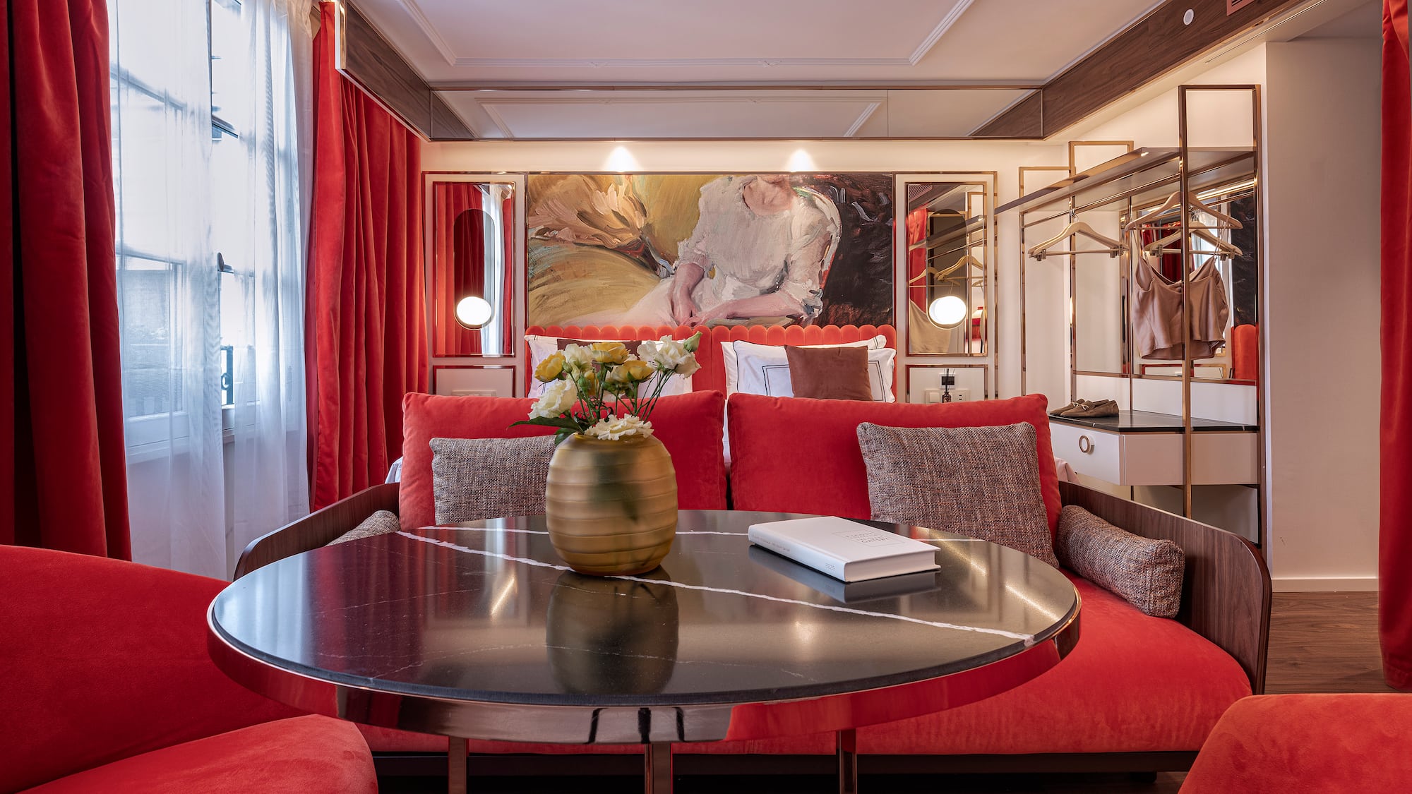 a room with red couches and a table with a vase of flowers