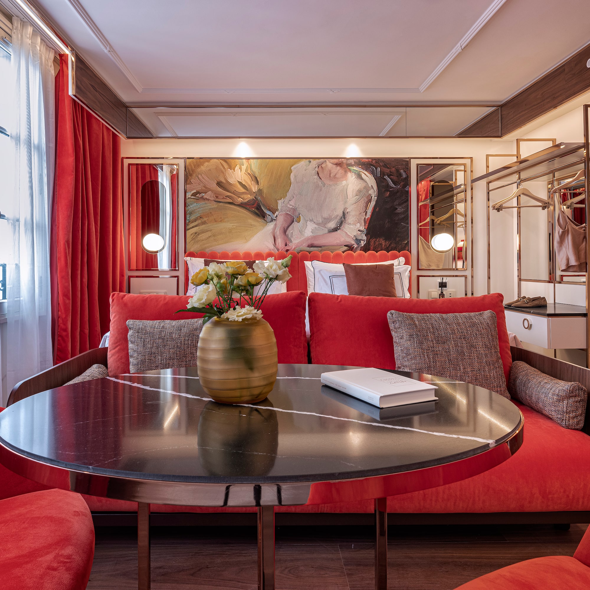 a room with red couches and a table with a vase of flowers