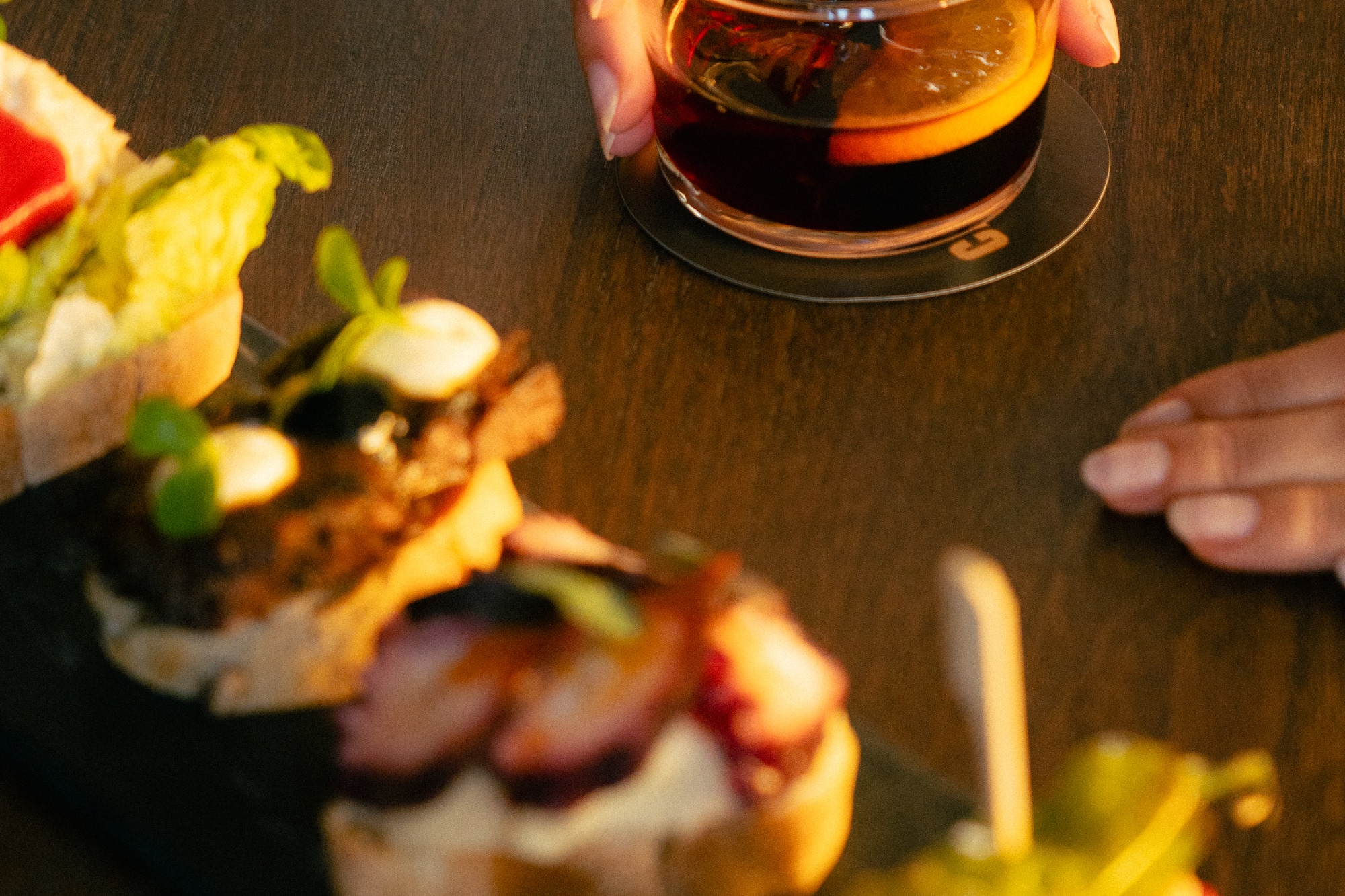 Hand with cocktail, alongside a platter of Spanish pintxos and tapas.