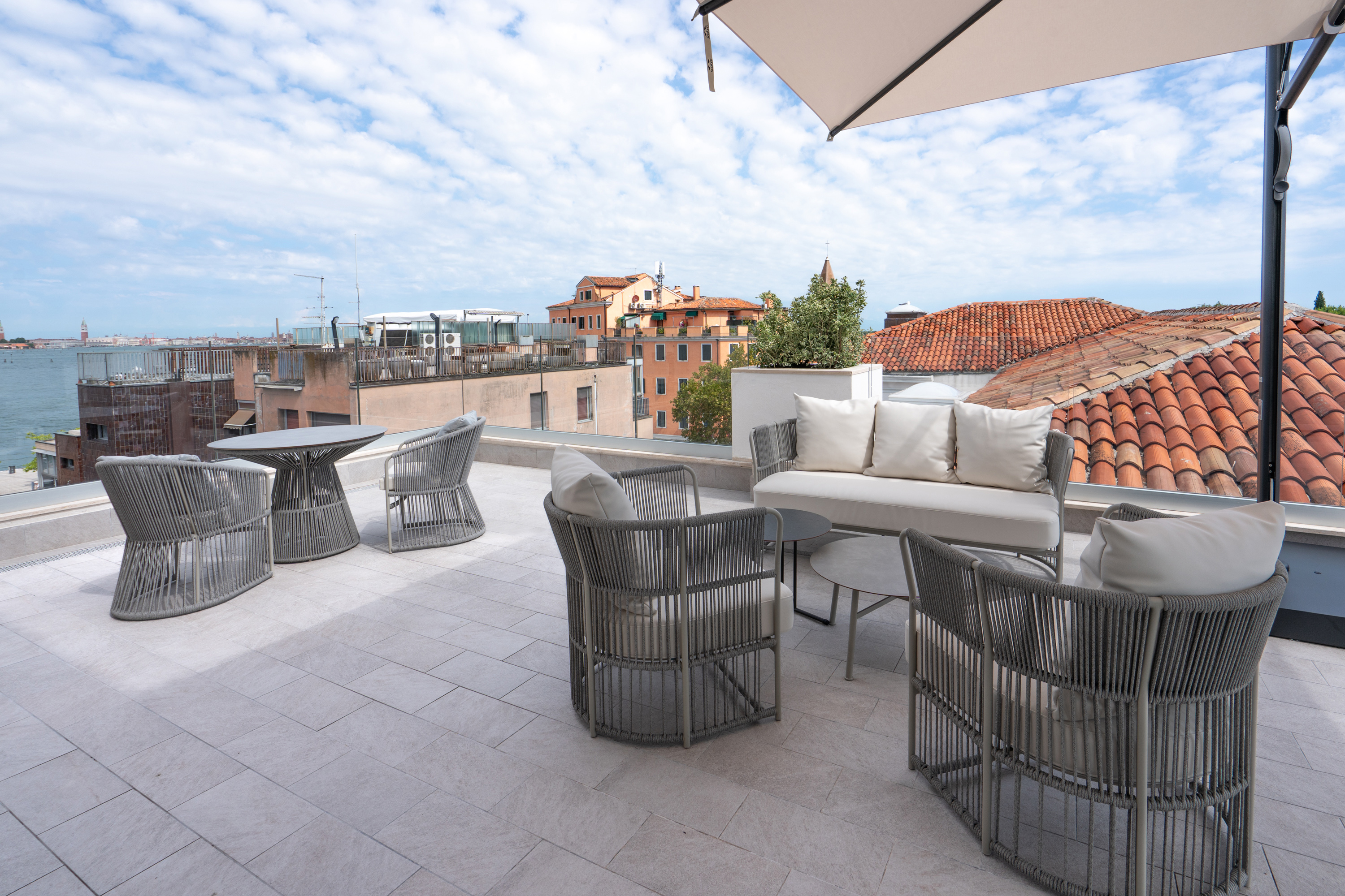 Modern grey outdoor furniture on Venice rooftop terrace with city views.