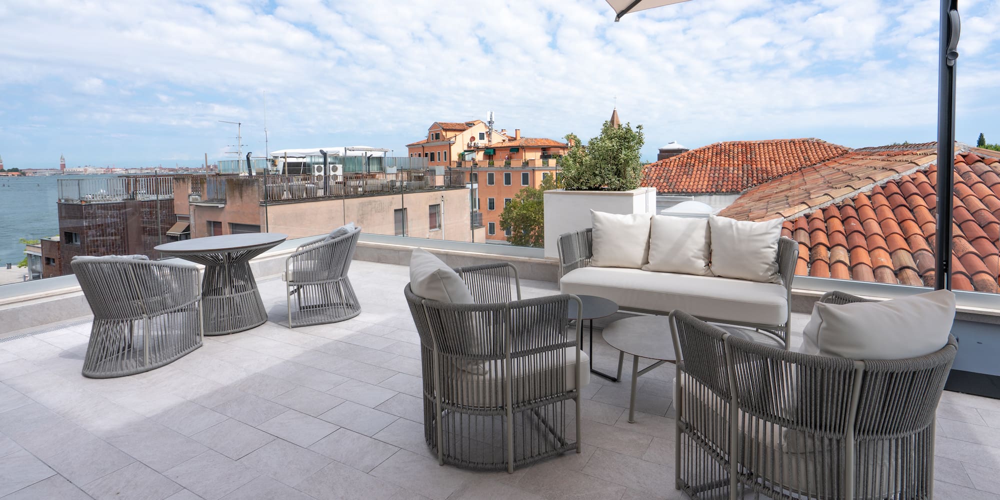Modern grey outdoor furniture on Venice rooftop terrace with city views.