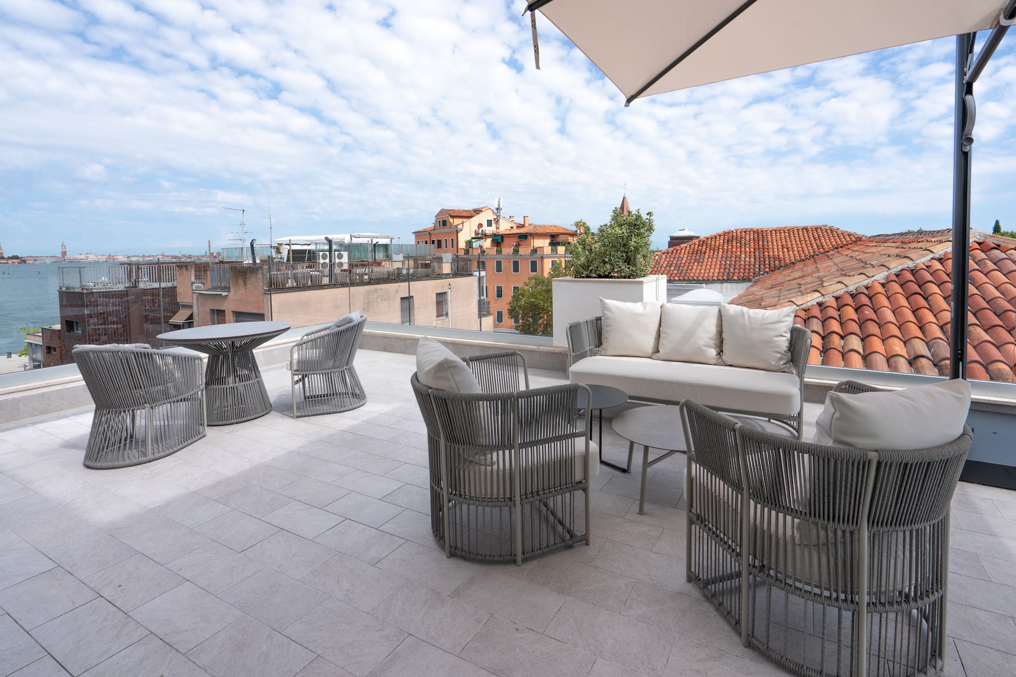Modern grey outdoor furniture on Venice rooftop terrace with city views.