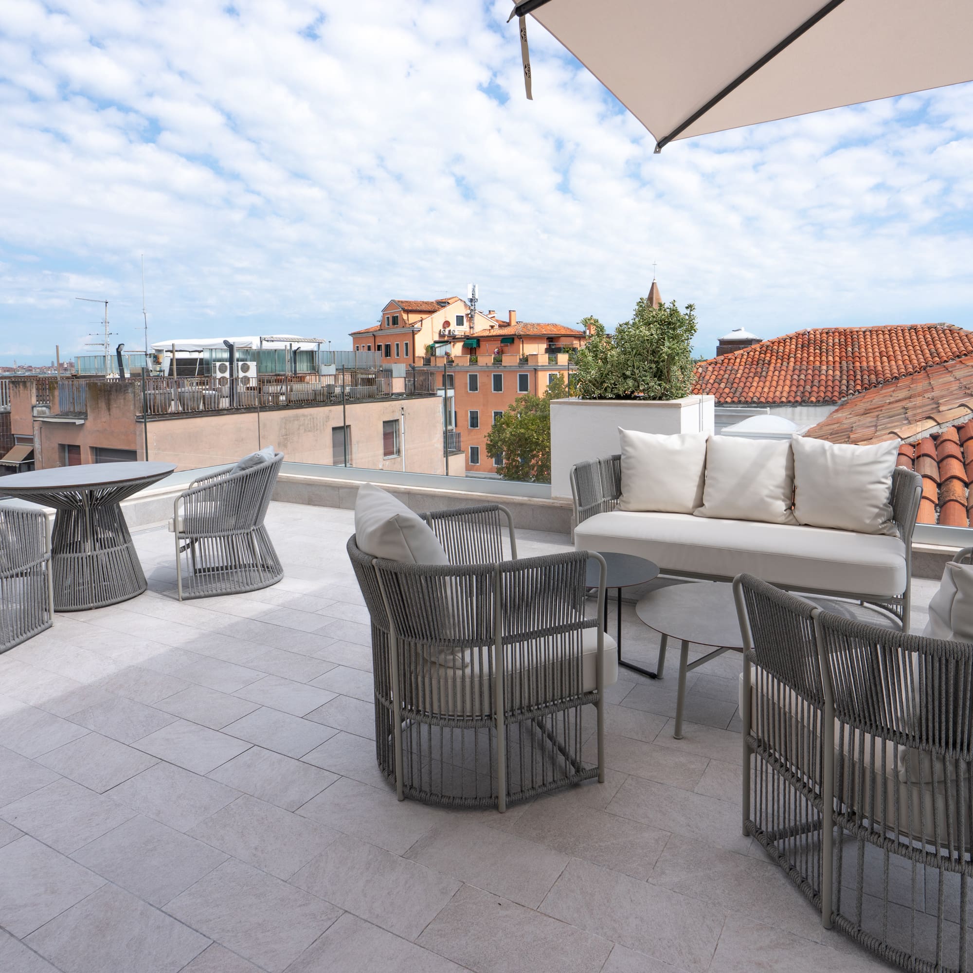 Modern grey outdoor furniture on Venice rooftop terrace with city views.