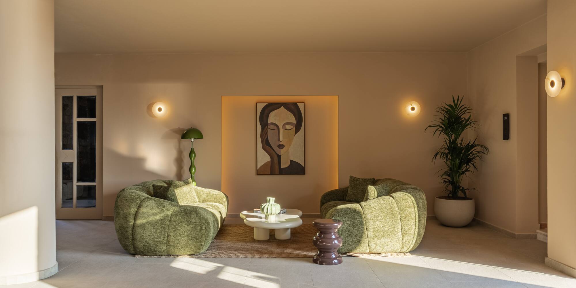Contemporary lounge with green chairs, abstract art, and minimalist design.