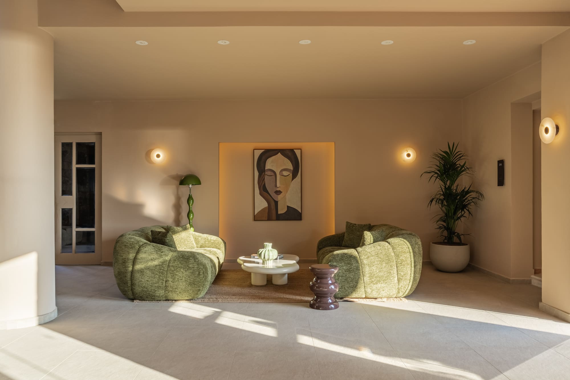 Contemporary lounge with green chairs, abstract art, and minimalist design.