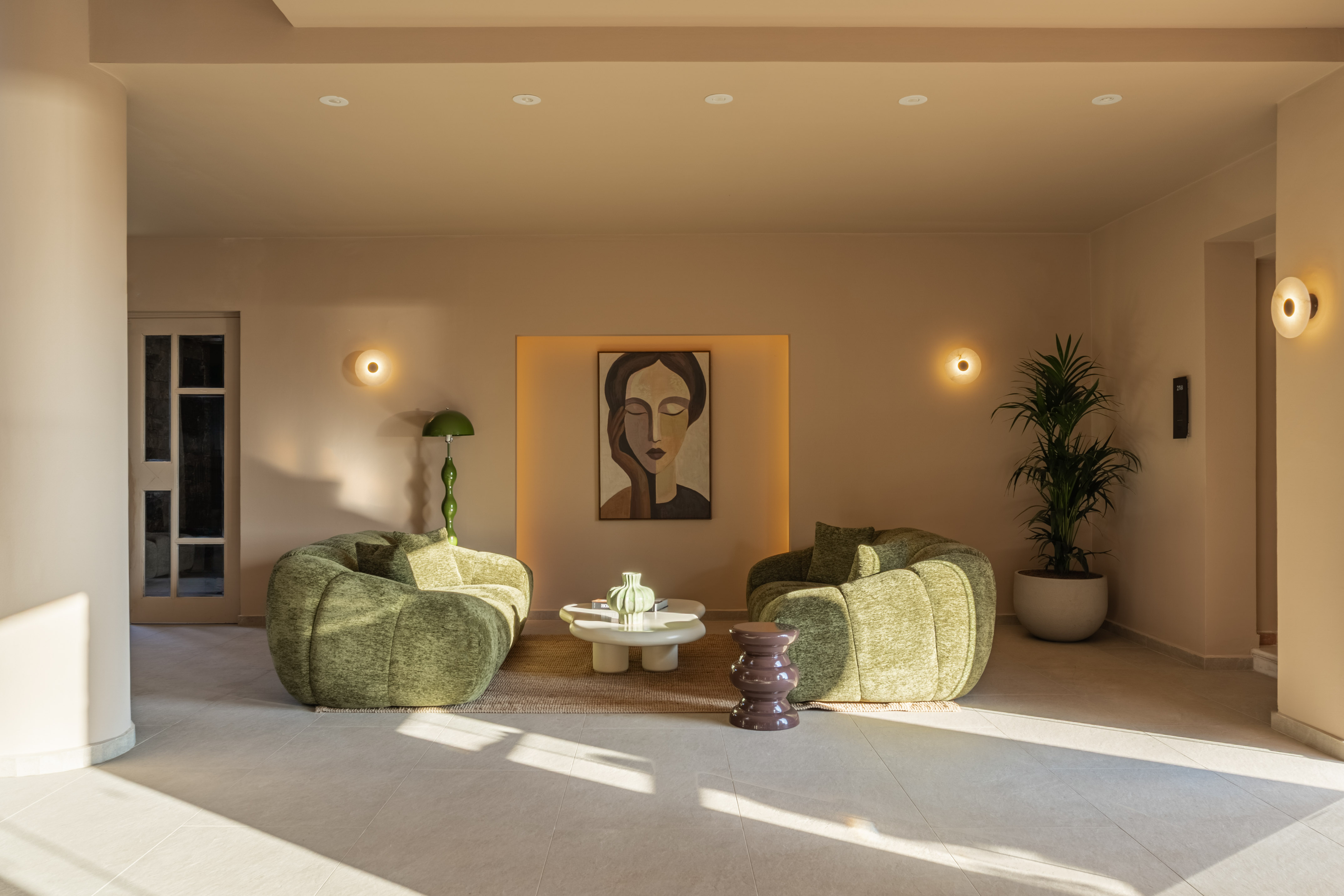 Contemporary lounge with green chairs, abstract art, and minimalist design.