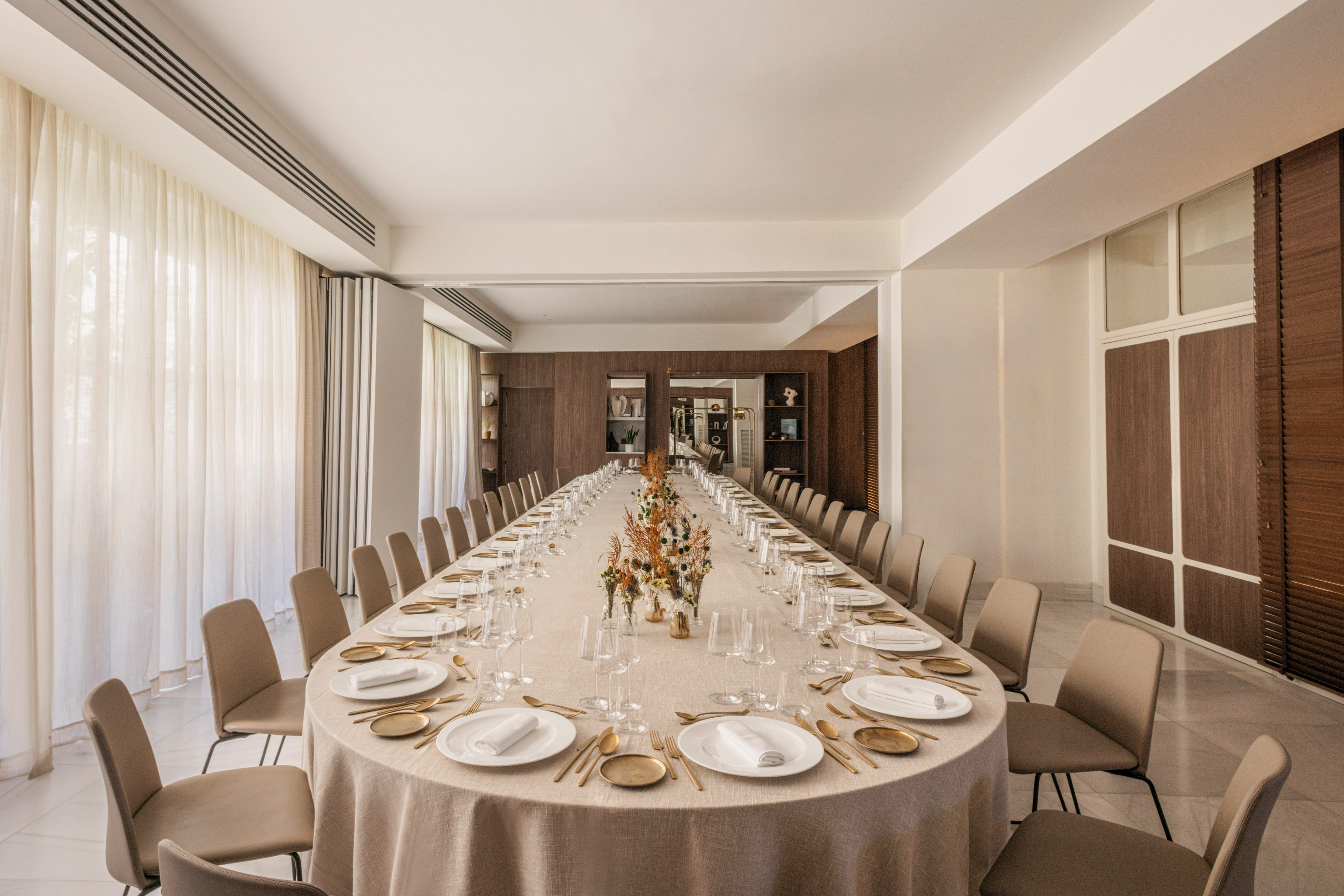 Elegant modern dining room with long oval table set for a banquet or meeting.
