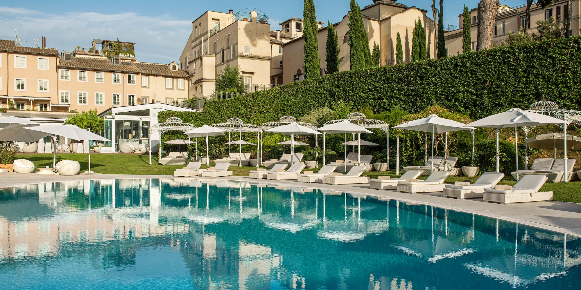 a pool with umbrellas and chairs in front of a building