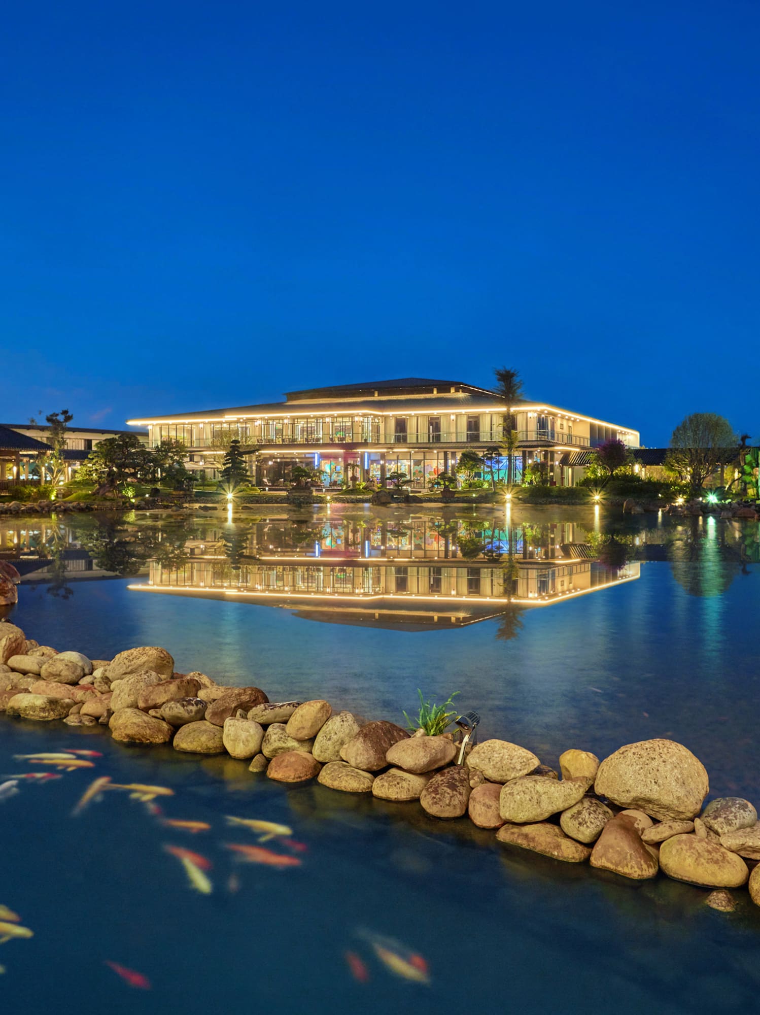 a pond with a building and fish swimming in it
