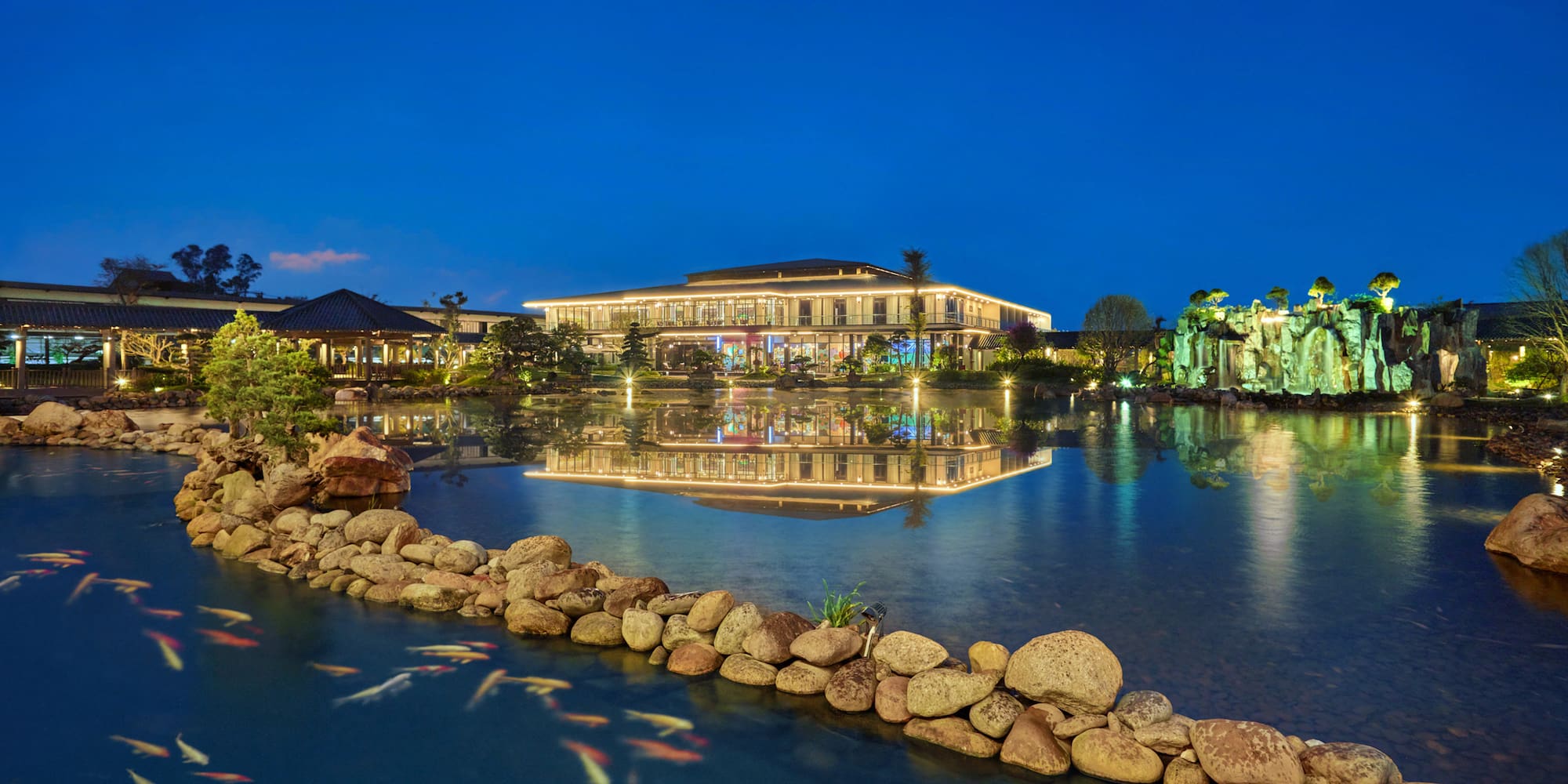 a pond with a building and fish swimming in it