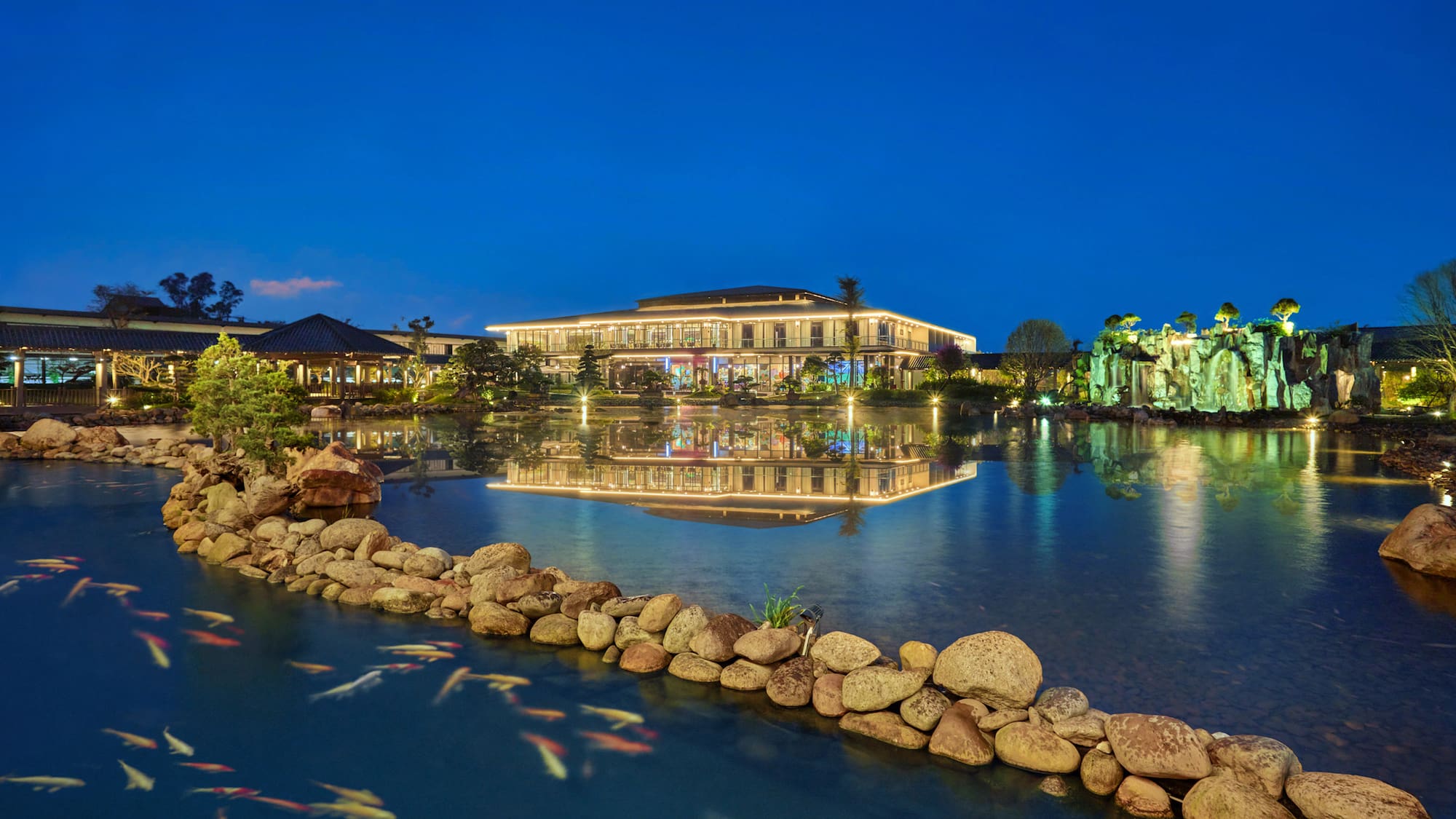 a pond with a building and fish swimming in it
