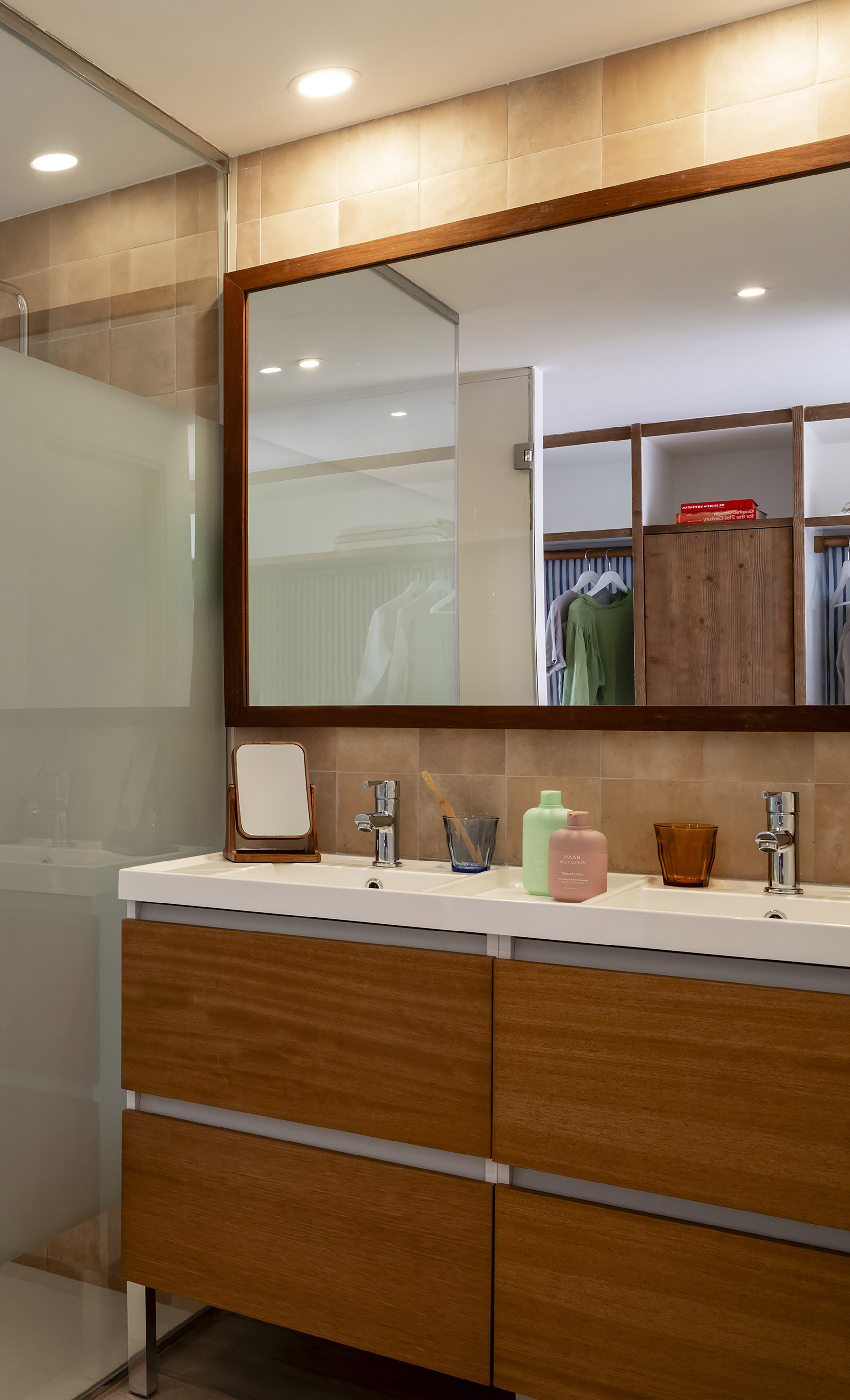 Modern bathroom with wood double sink vanity, large mirror, and tiled walls.