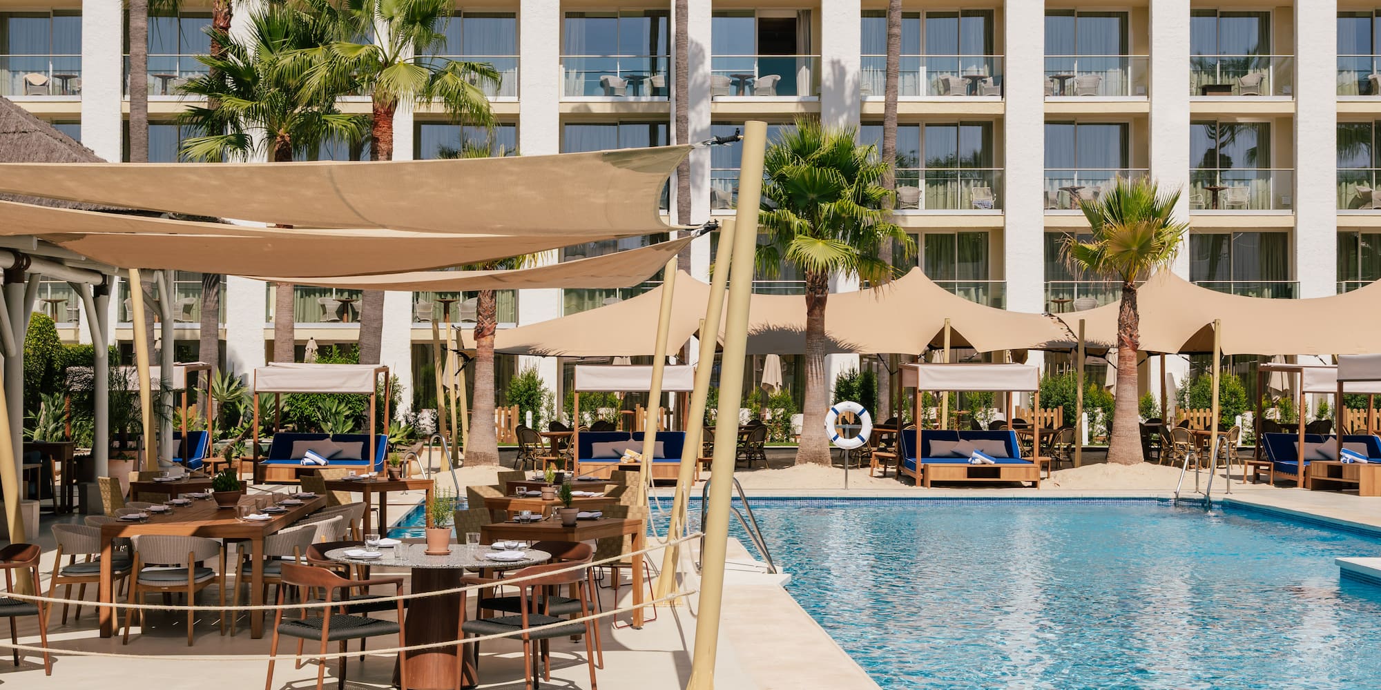 a pool with tables and chairs in front of a building