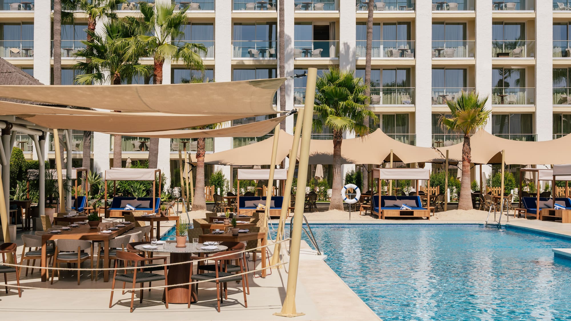a pool with tables and chairs in front of a building