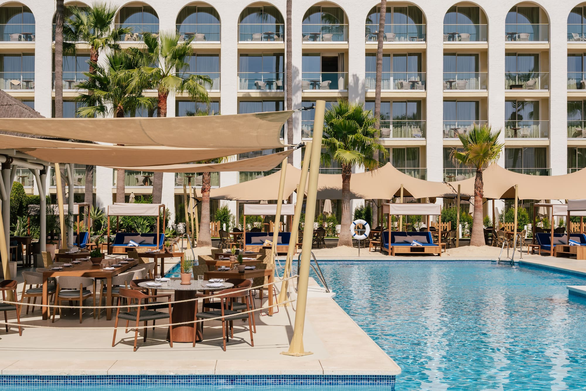 a pool with tables and chairs in front of a building