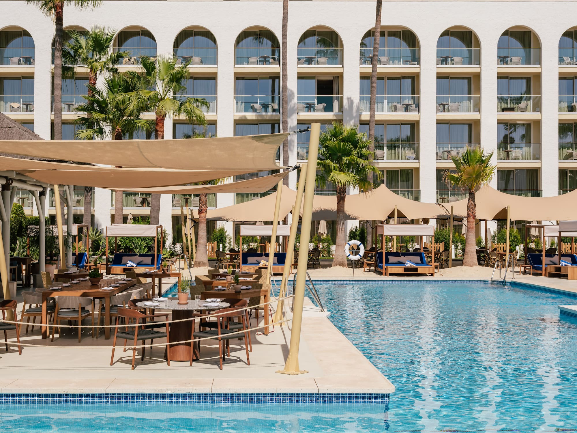 a pool with tables and chairs in front of a building