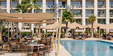 a pool with tables and chairs in front of a building