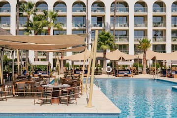 a pool with tables and chairs in front of a building