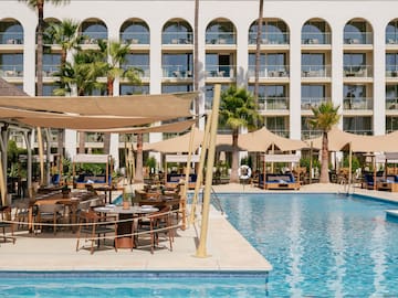 a pool with tables and chairs in front of a building