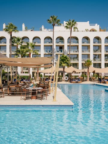 a pool with tables and chairs in front of a building