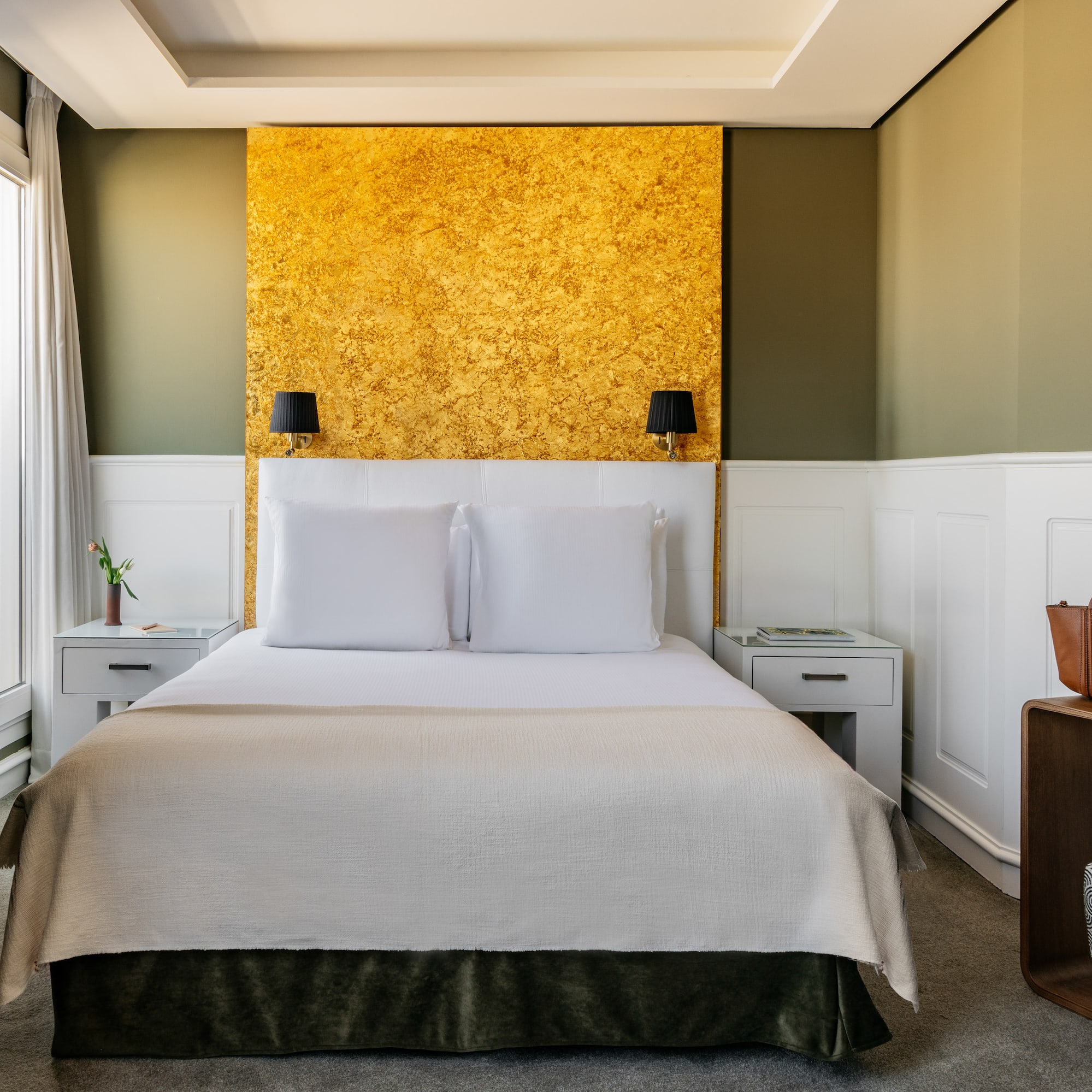 a bed with white pillows and a gold wall