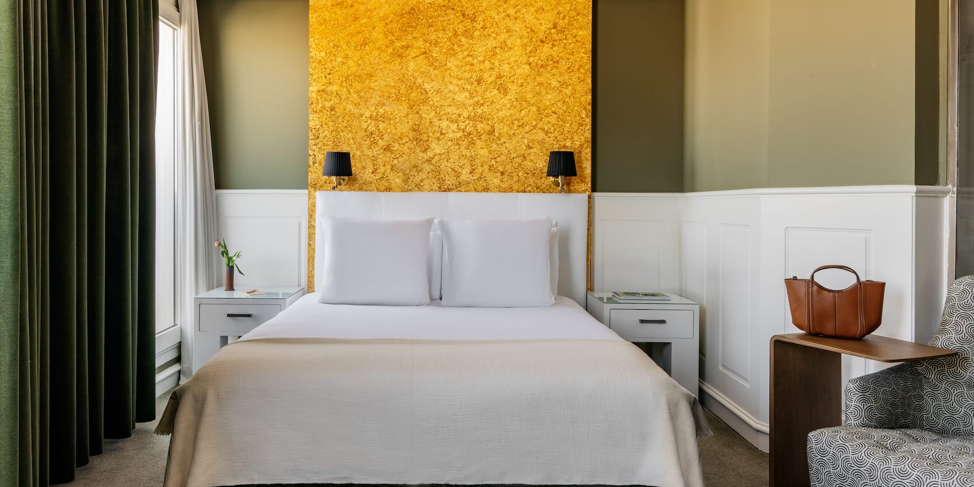 a bed with white pillows and a gold wall