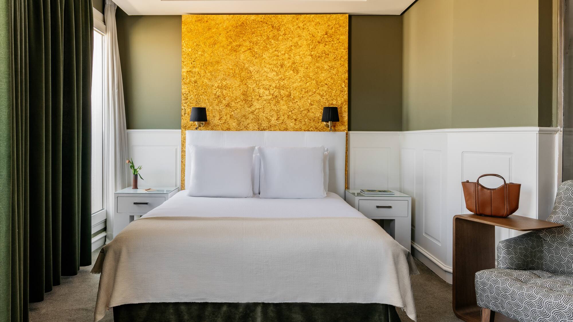 a bed with white pillows and a gold wall