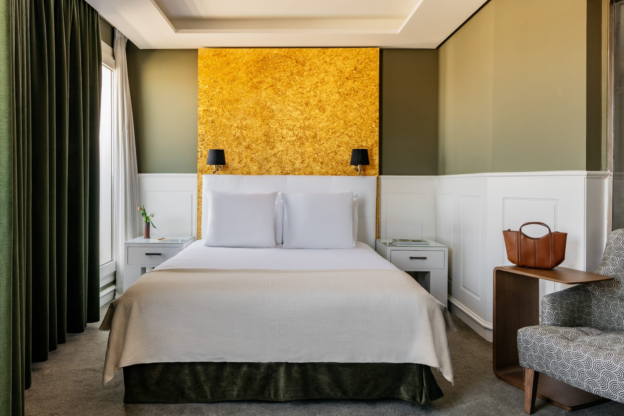 a bed with white pillows and a gold wall
