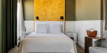 a bed with white pillows and a gold wall