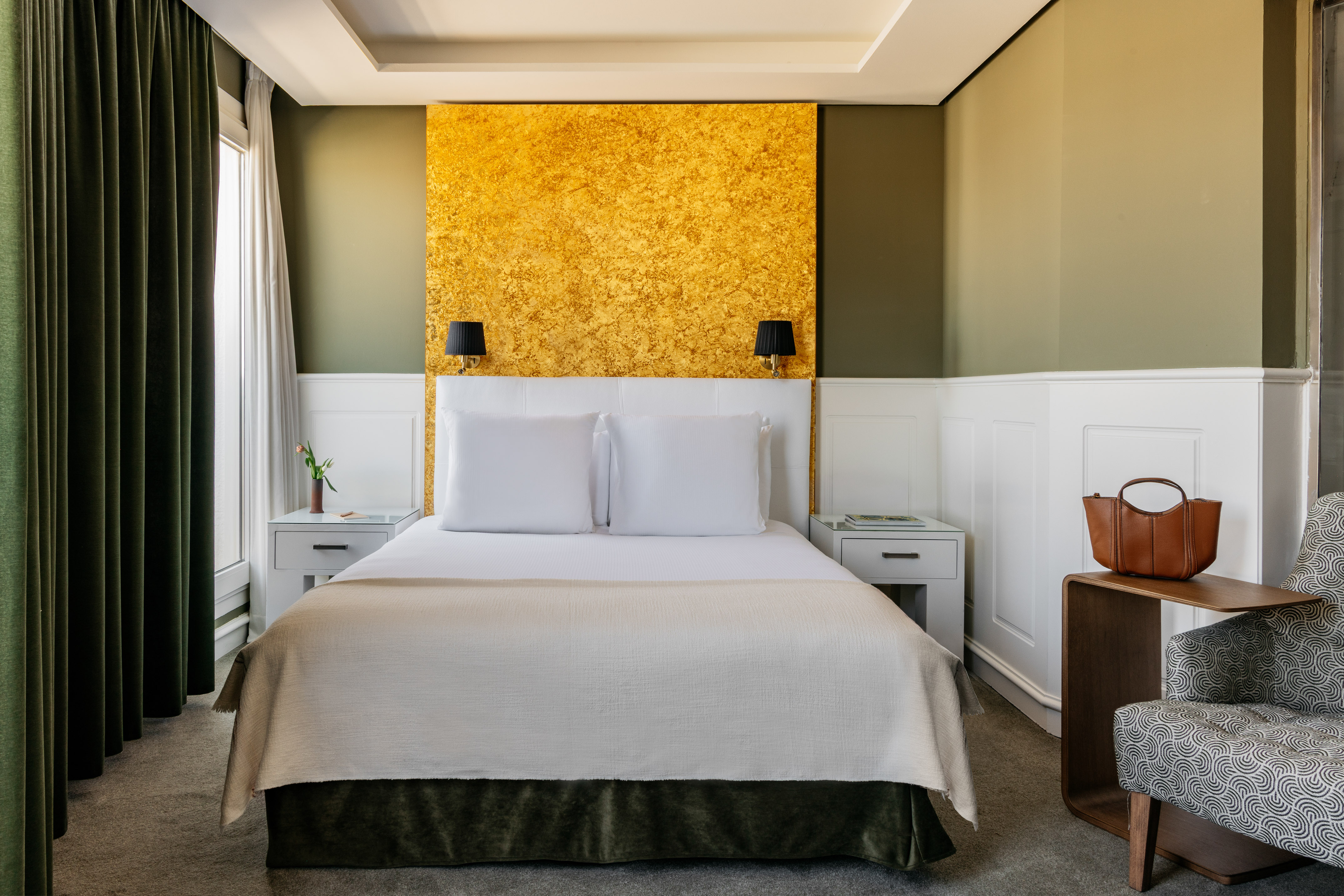 a bed with white pillows and a gold wall