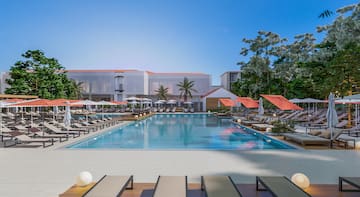 a pool with umbrellas and chairs in front of a building