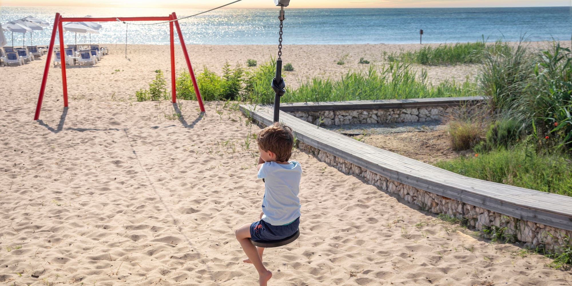 ein Junge auf einer Schaukel am Strand
