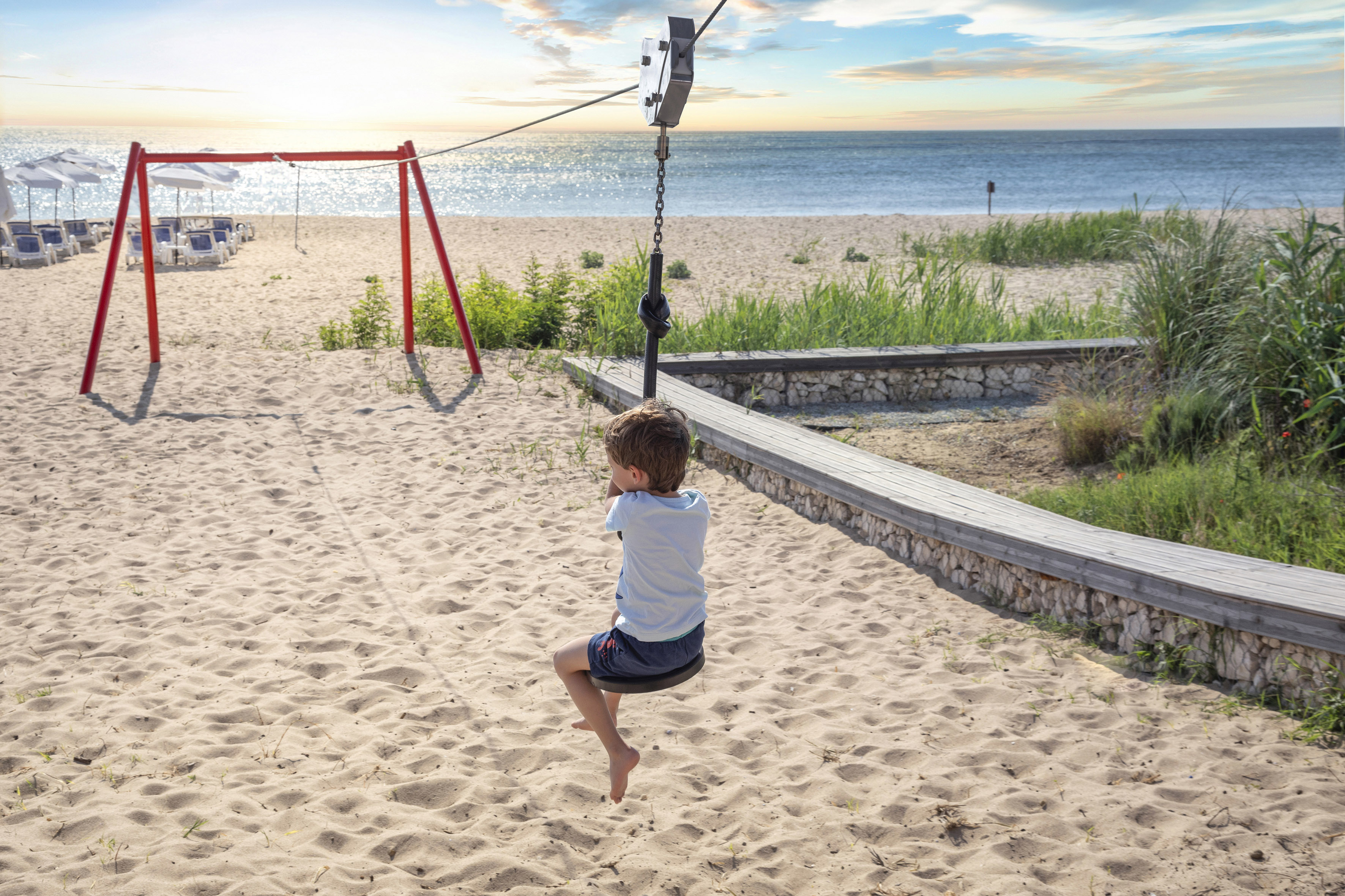 ein Junge auf einer Schaukel am Strand
