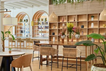 a room with a table and chairs and shelves with plants
