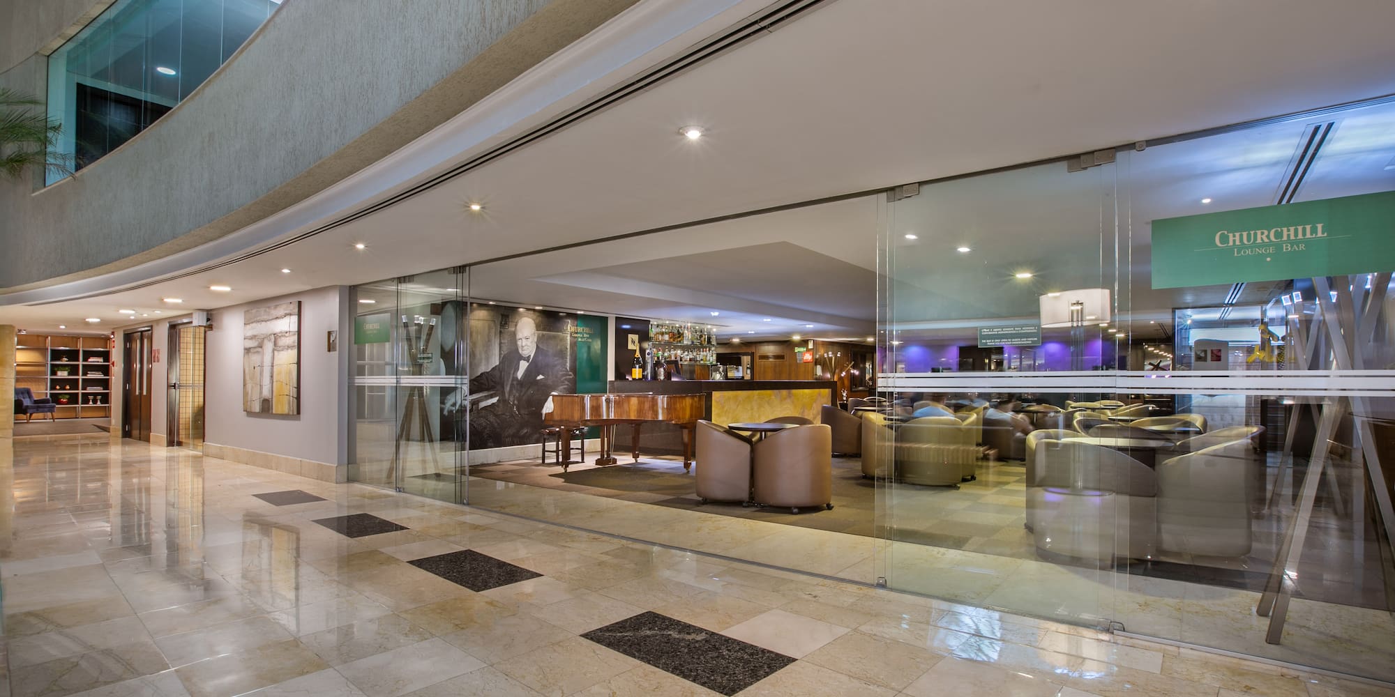 Churchill Lounge Bar entrance in a hotel lobby with piano and cozy seating.