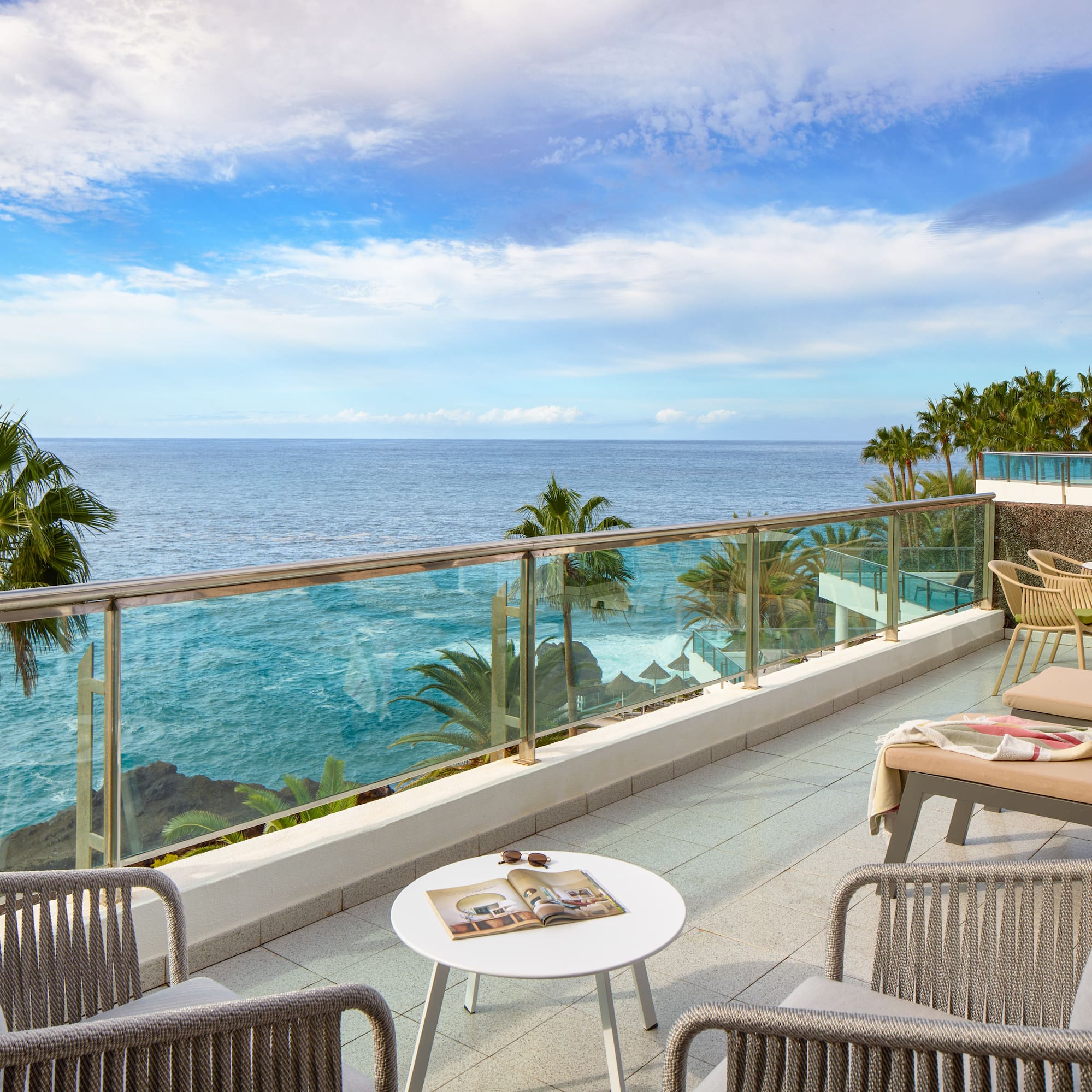 a patio with a glass railing and chairs and a table