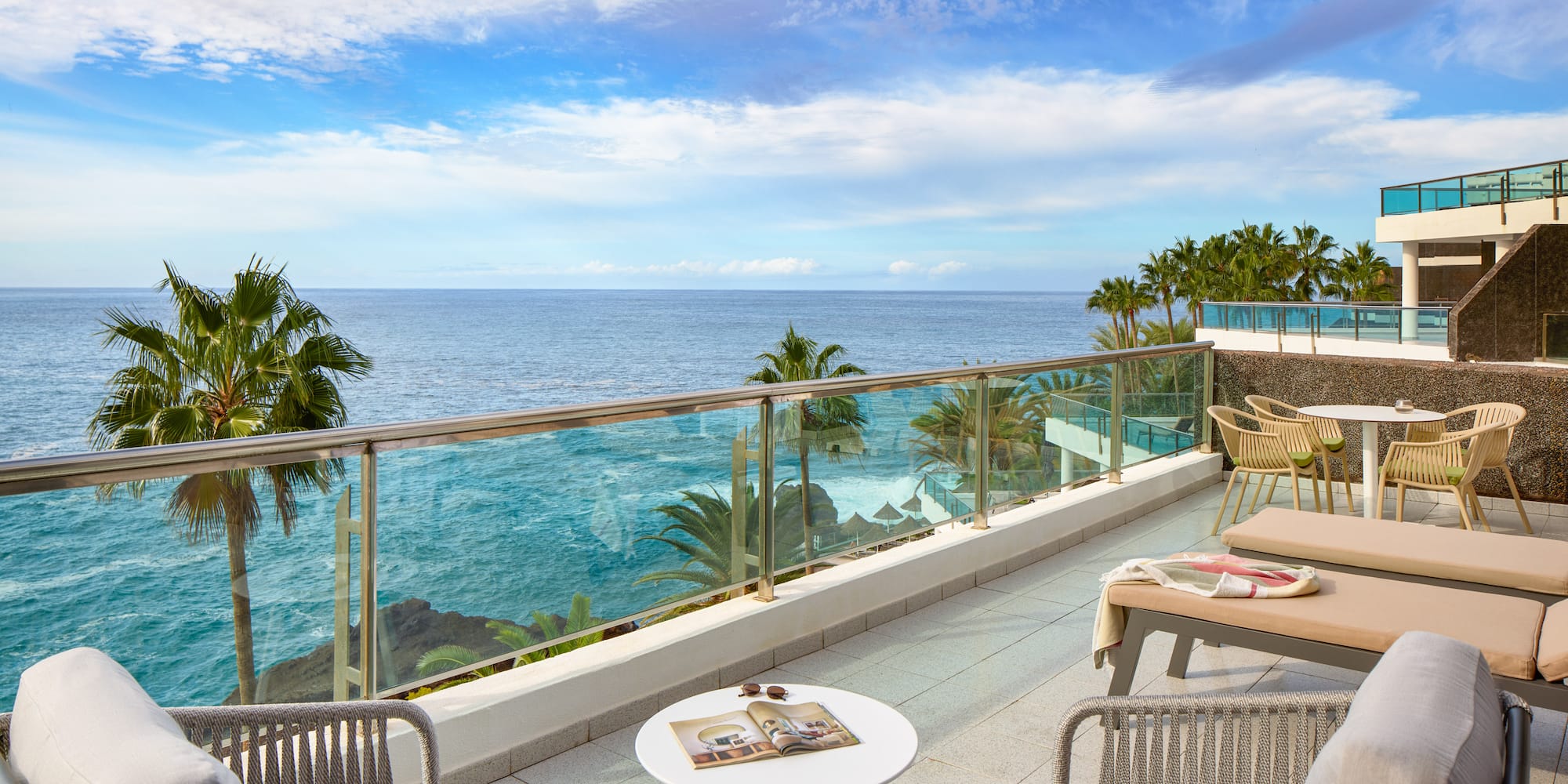 a patio with a glass railing and chairs and a table