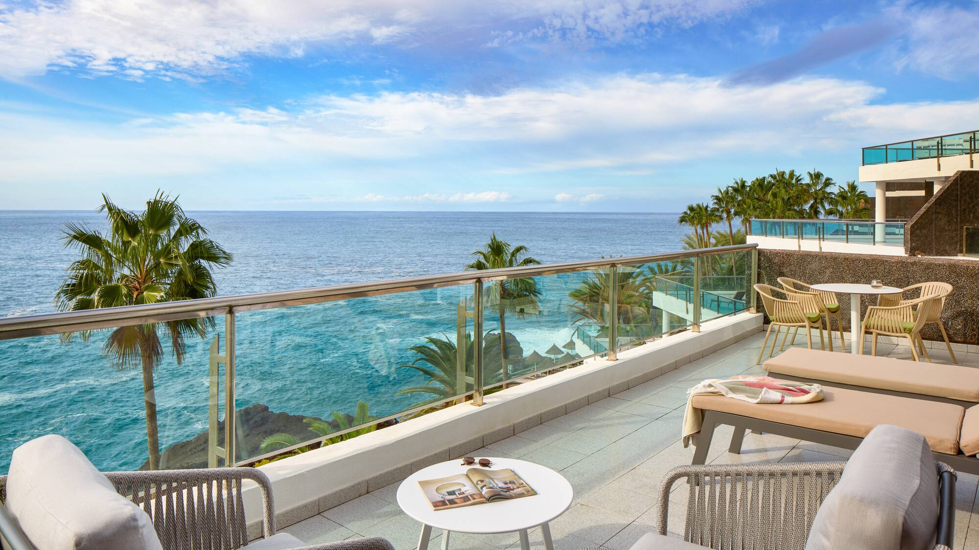 a patio with a glass railing and chairs and a table