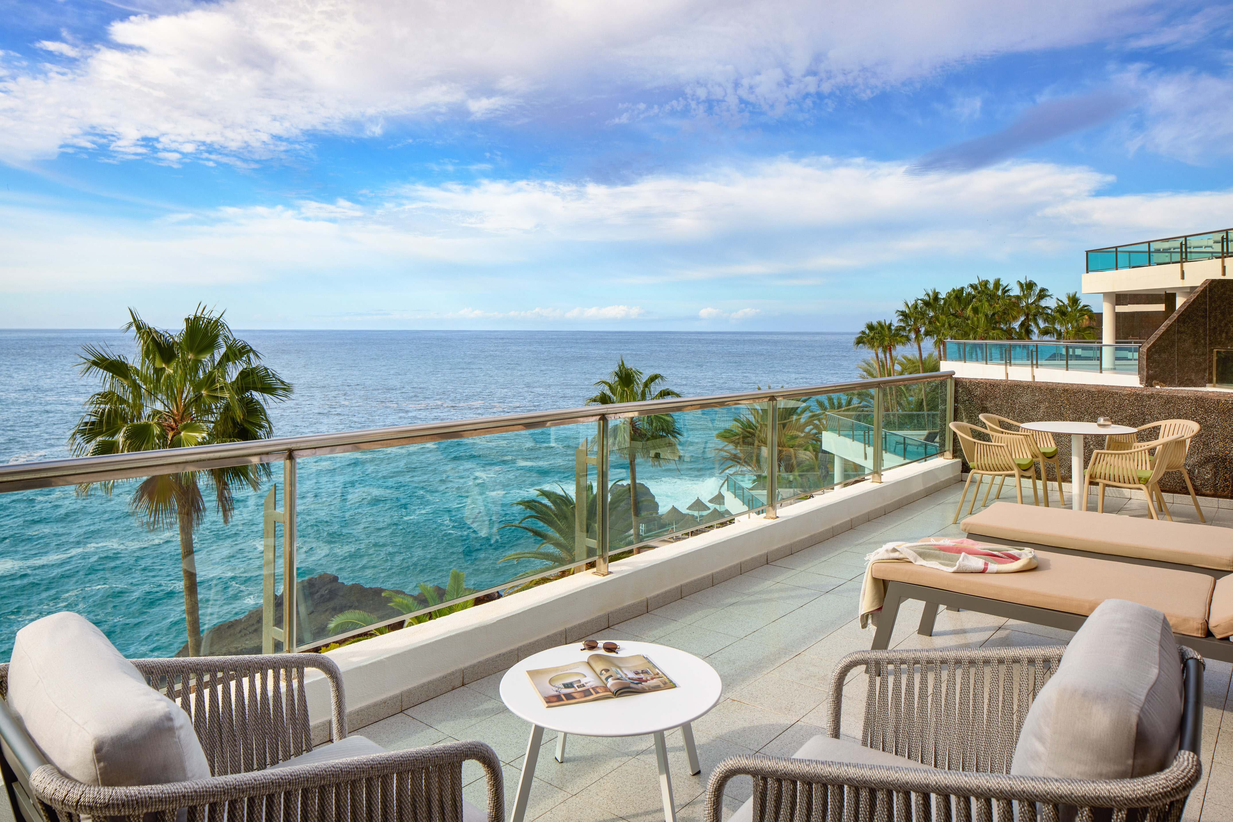 a patio with a glass railing and chairs and a table