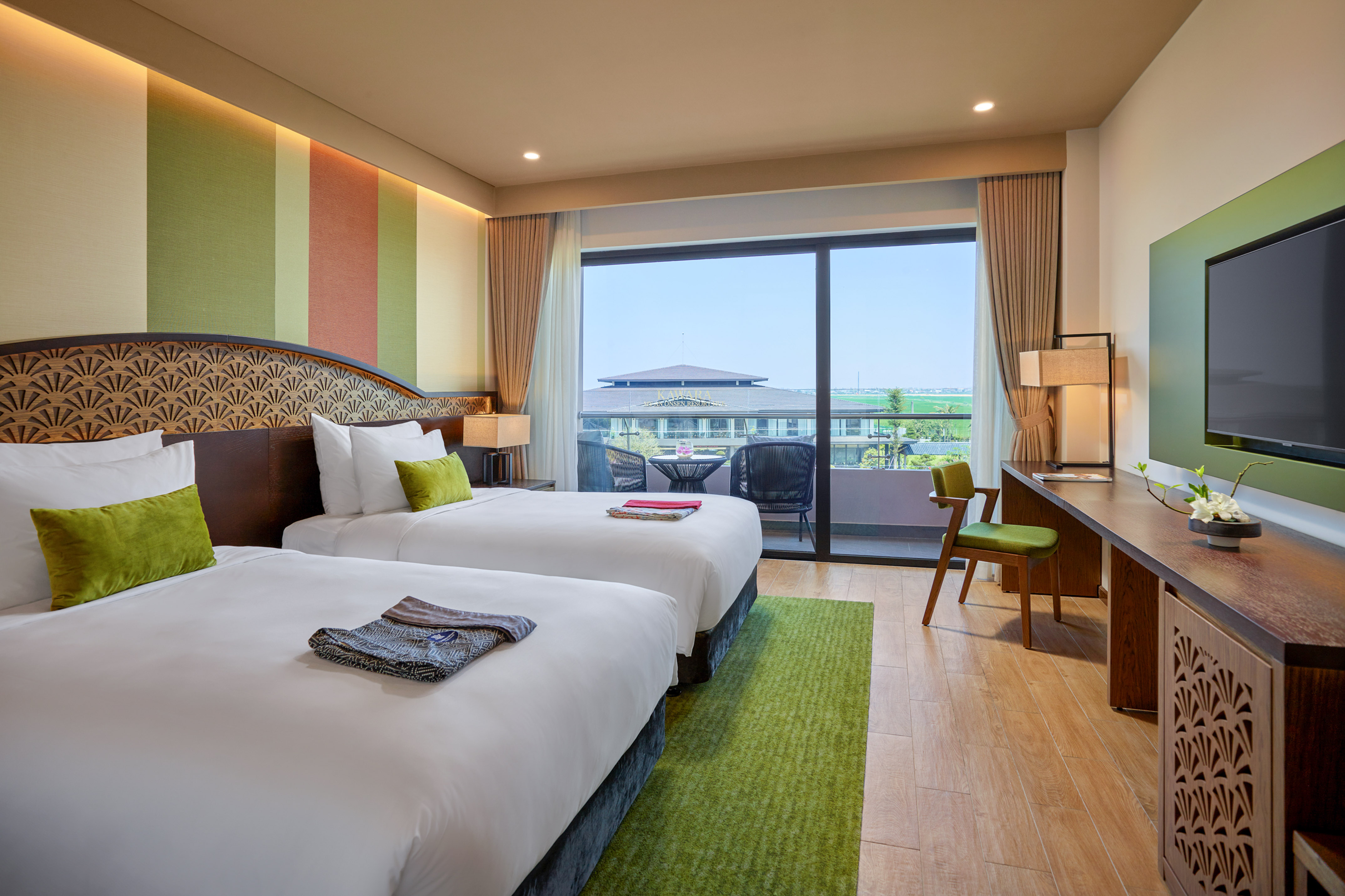 Luxurious hotel room with twin beds, green decor, private balcony, resort view.