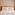 Modern hotel bedroom with wooden headboard, pink pillows, and plaid throw blanket.