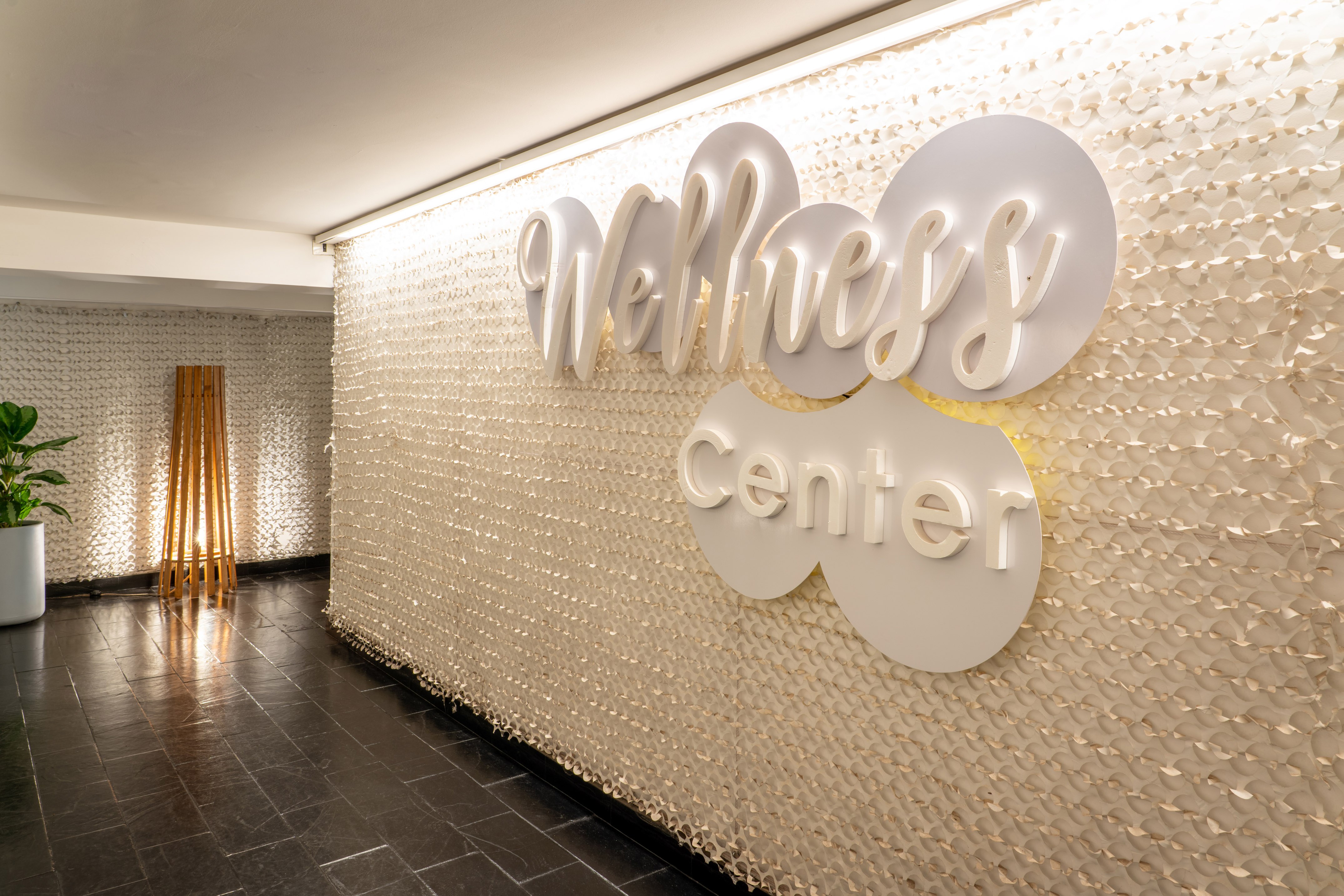 Wellness Center entrance with illuminated sign on decorative textured wall.