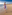 Woman in purple summer dress running barefoot on a sunny beach.