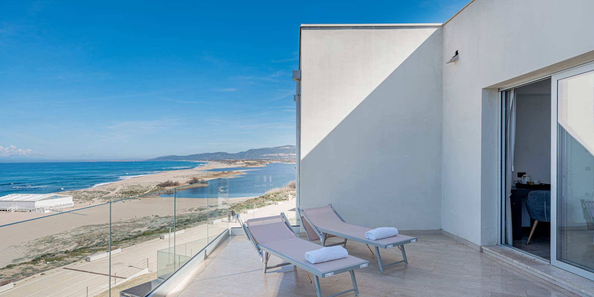 a deck with chairs and towels on a balcony overlooking a beach