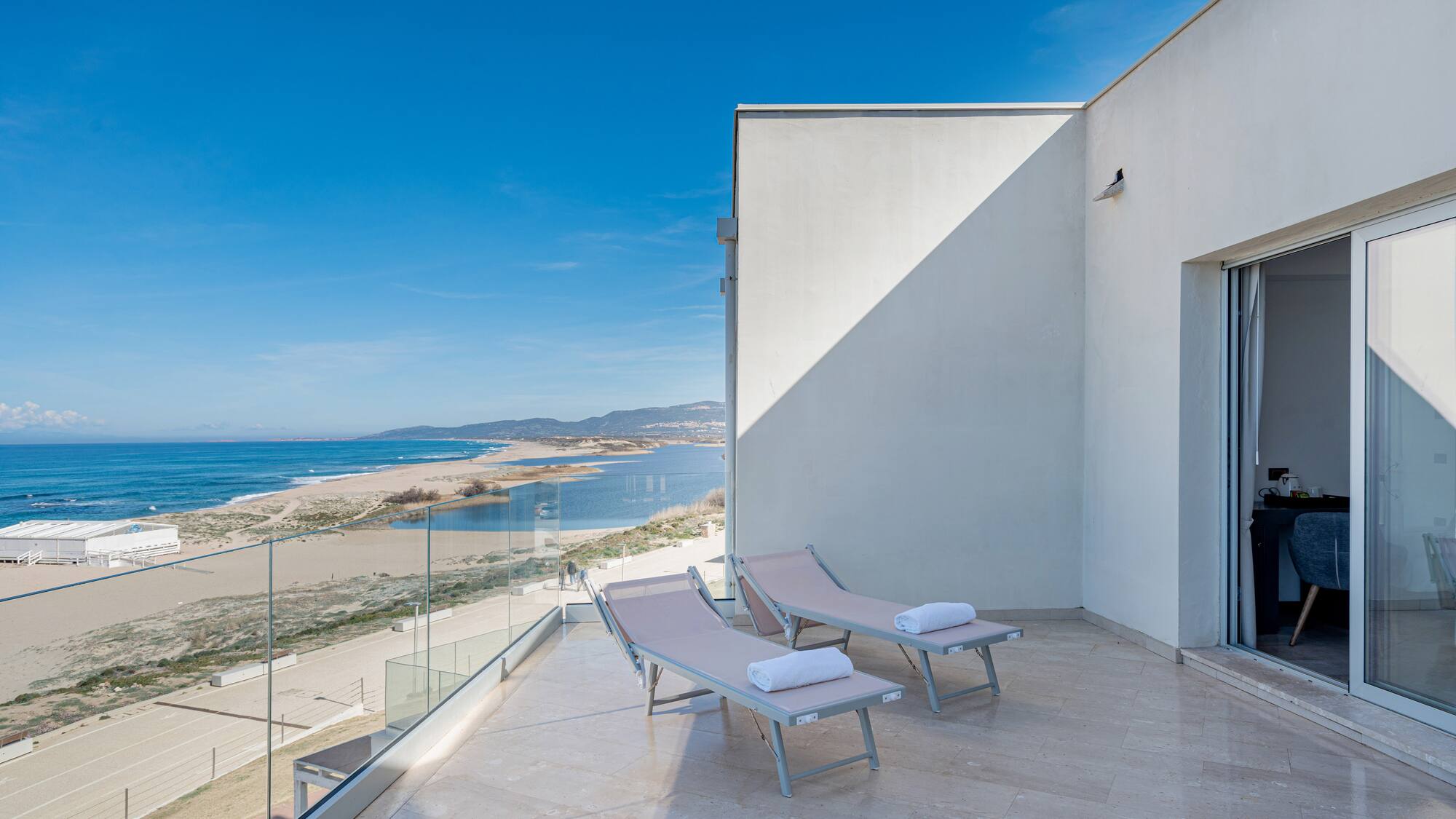 a deck with chairs and towels on a balcony overlooking a beach