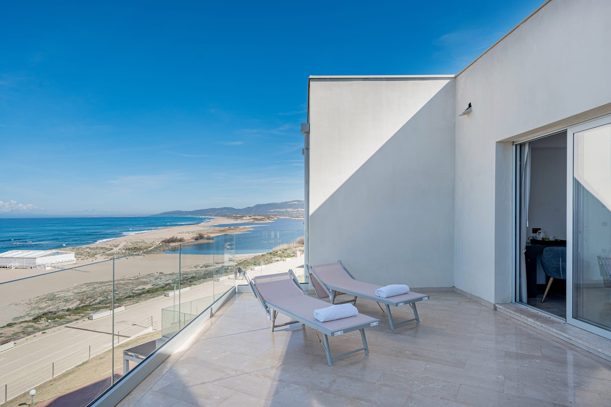 a deck with chairs and towels on a balcony overlooking a beach