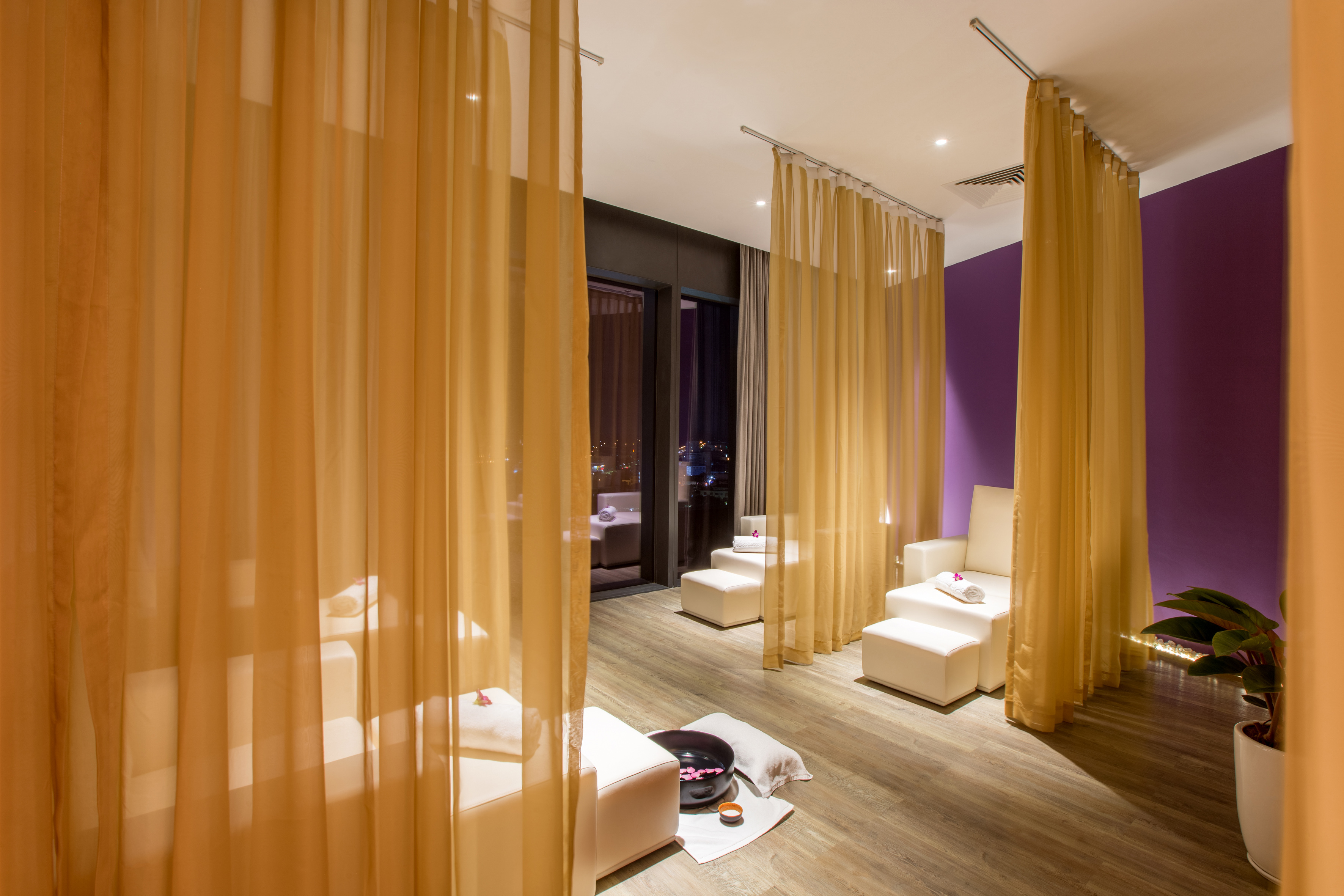 Spa foot massage area with white chairs, sheer curtains, and purple wall.