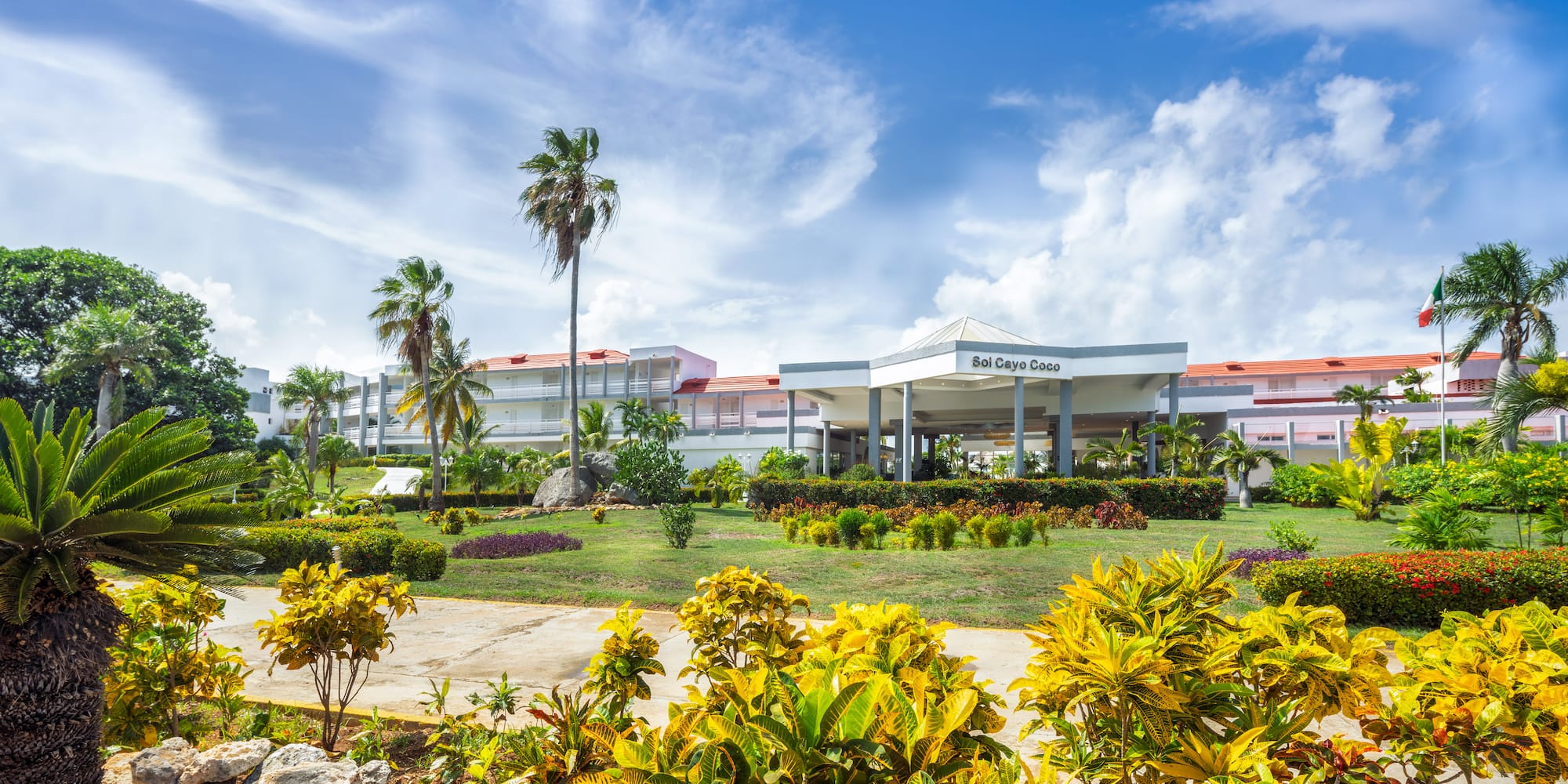 a building with a large front yard and palm trees